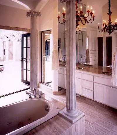 A luxurious bathroom design featuring a large jacuzzi tub, elegant columns, a chandelier, and a spacious vanity with mirrors, created by Rockridge Builders in Oakland.