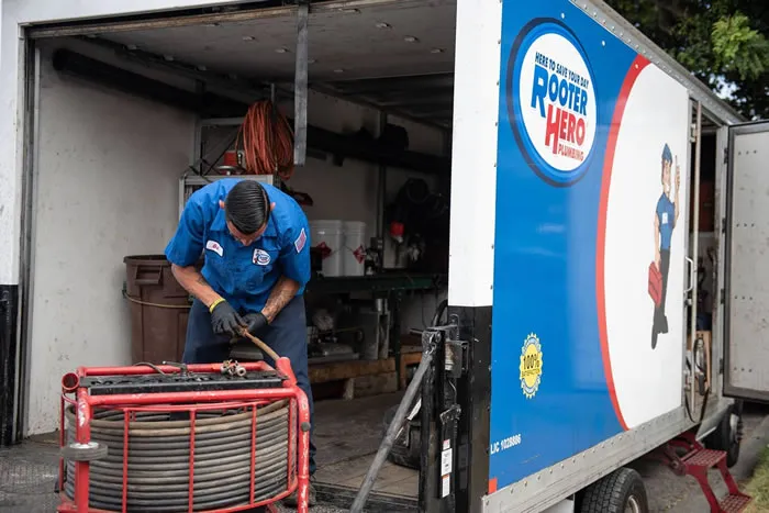 "A technician from Rooter Hero Plumbing working on equipment in the back of a company truck in Martinez."