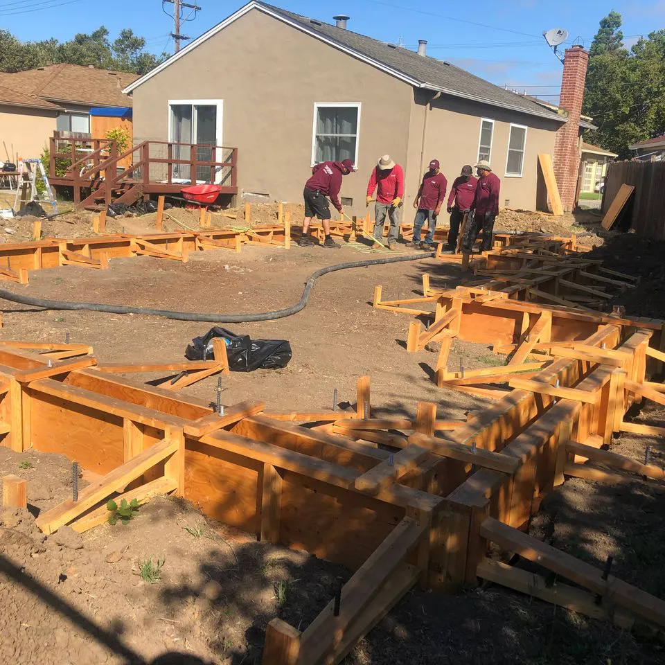 Construction workers from SF Craftsman, Inc. set up wooden forms for a concrete foundation at a building site in San Francisco.