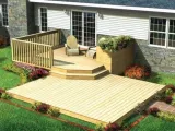 A beautifully landscaped wooden deck attached to a house, featuring seating and planters, surrounded by a well-maintained garden.