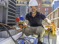 Technician in a hard hat servicing HVAC equipment on a rooftop, representing SanJoseHeating&Cooling in SanJose.