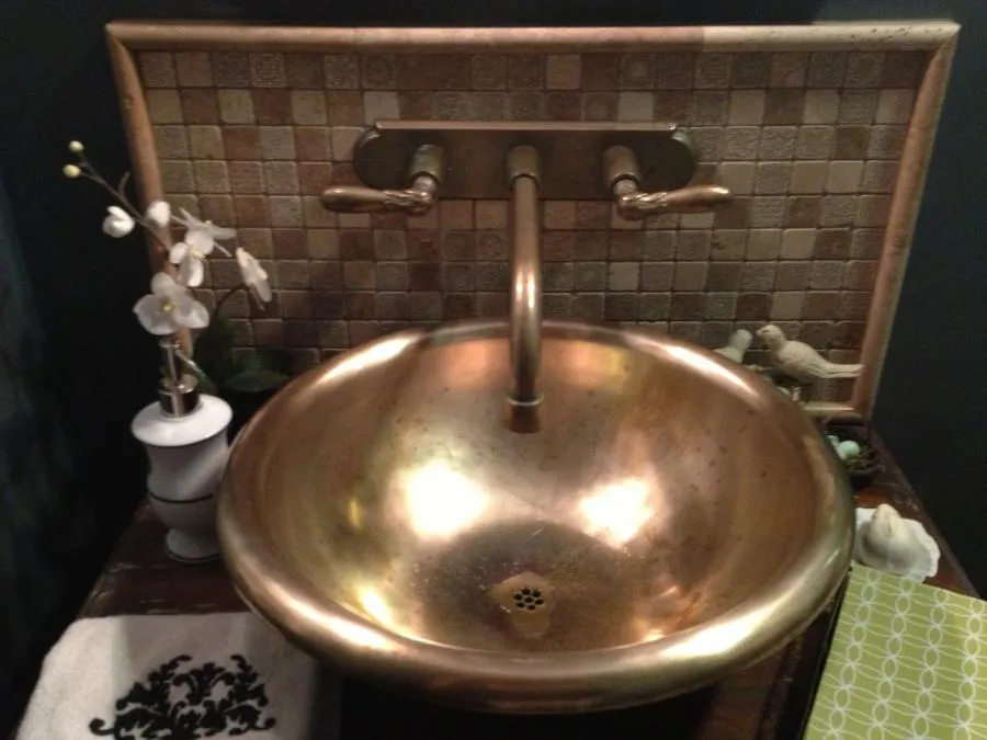A luxurious brass sink with wall-mounted fixtures beside a flower vase, installed by Savior Plumbing, Inc. in Pleasanton.