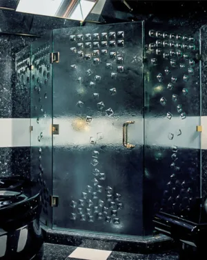 A luxurious shower enclosure with textured glass panels and gold hardware, located in a contemporary bathroom.