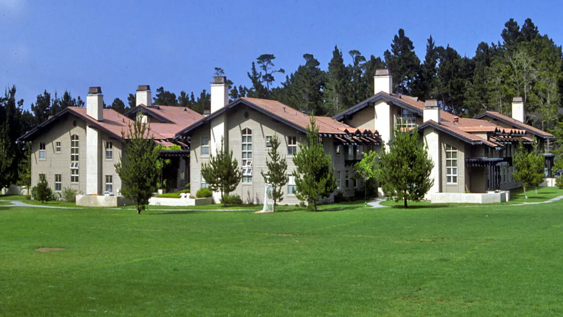A residential building in Monterey with distinct roofing by Scudder Roofing Company, set amidst lush greenery and surrounded by trees.