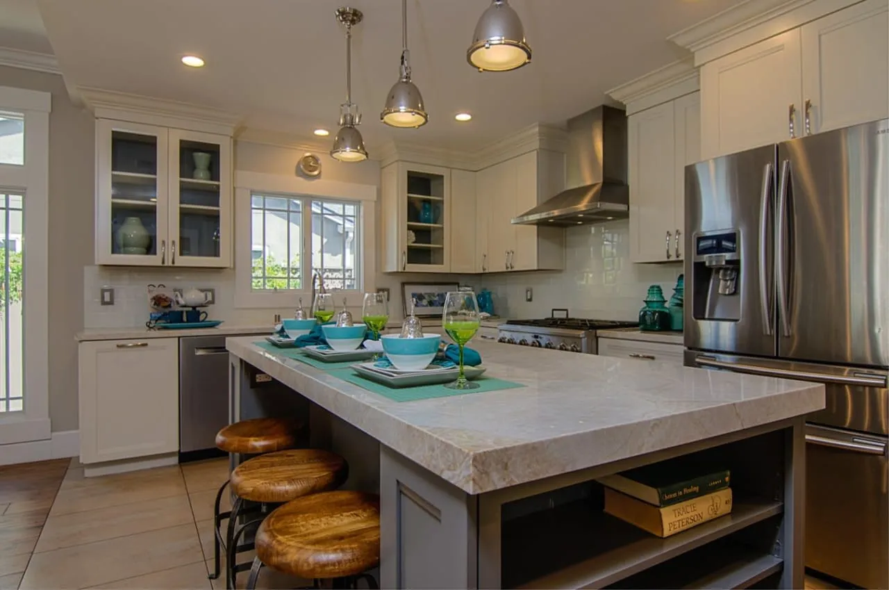 A modern kitchen in San Jose featuring a large marble island, stainless steel appliances, and stylish lighting, presented by Sheila Santwani Real Estate.