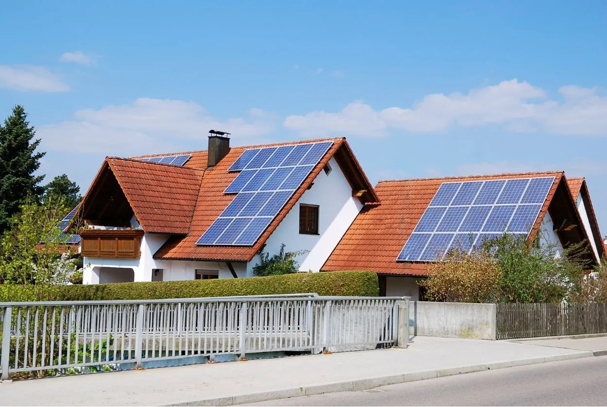 A house with red-tiled roofs fitted with solar panels, set against a clear blue sky, representing sustainable energy solutions by Sierra Roofing & Solar in Dublin.