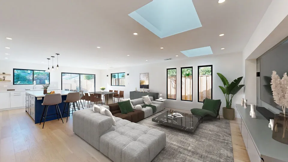 A modern, open-plan living room and kitchen with skylights, sleek furniture, and wooden flooring, designed by Sigura Construction, Inc. in San Jose.