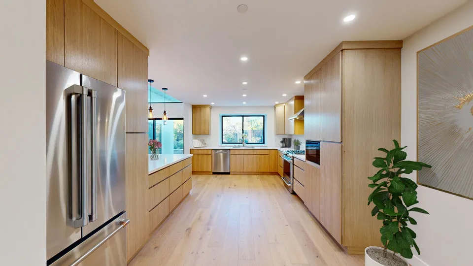 A modern kitchen with wooden cabinets, recessed lighting, stainless steel appliances, and a large window, designed by Sigura Construction, Inc. in San Jose.