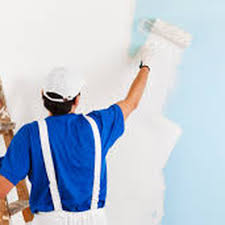 A painter in blue overalls applying white paint to a wall with a roller, representing Sigura Pro Painting in San Jose.