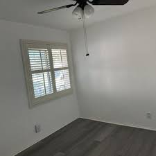 A freshly painted room with white walls, a window with shutters, and a ceiling fan, showcasing the work of Sigura Pro Painting in San Jose.