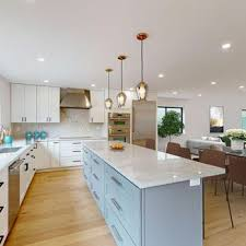 A modern kitchen with white cabinets, a large island, and pendant lights, showcasing a refined interior design by Sigura Pro Painting in San Jose.