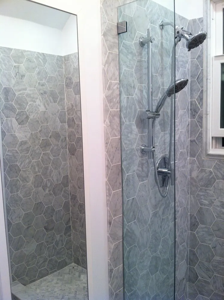 Modern shower with hexagonal marble tiles and dual shower heads, designed by Simple Builders in Winnetka.