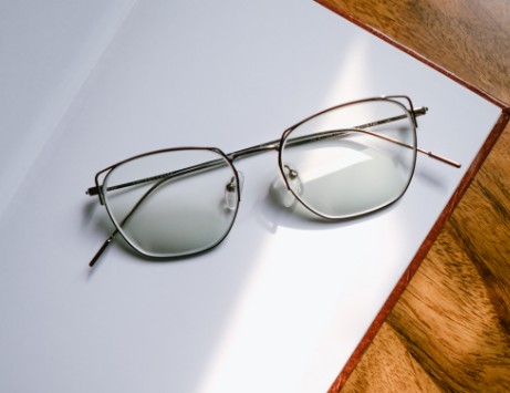 A pair of stylish eyeglasses resting on an open notebook, with sunlight streaming in, symbolizing clarity and vision.