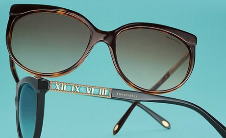 A pair of stylish, tortoiseshell sunglasses with Roman numeral detailing, set against a turquoise background, showcasing elegance and craftsmanship.