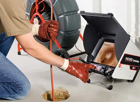 A plumber in gloves using inspection equipment to examine pipes, showcasing advanced tools in Santa Clara by Smart Plumbers, Inc.