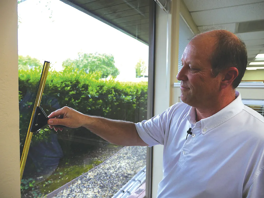 "A person from Smart Window Cleaning in Novato using a squeegee to clean a glass window, demonstrating professional cleaning techniques."