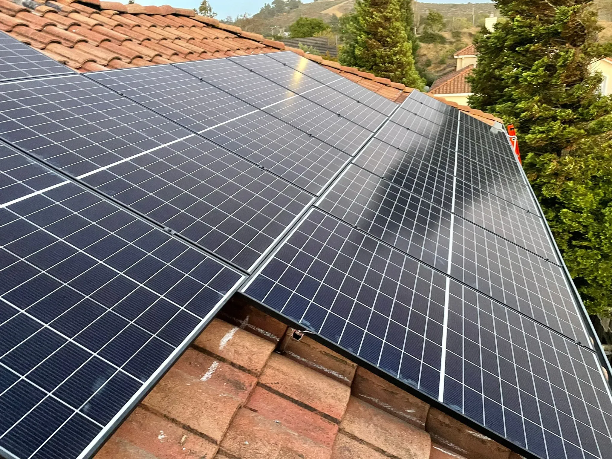 A rooftop in San Francisco equipped with multiple solar panels installed by SolarUnion, surrounded by trees and distant hills.