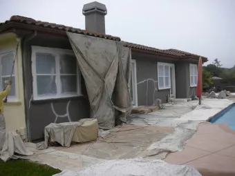 A house in the process of being painted, with tarps covering the ground and parts of the house, done by Solidarity Painting, Inc. in Santa Rosa.