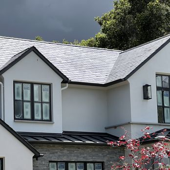 A close-up of a house with a well-maintained roof, showcasing expert craftsmanship by South Creek Roofing & Waterproofing Inc. in San Jose, with dark clouds in the background.