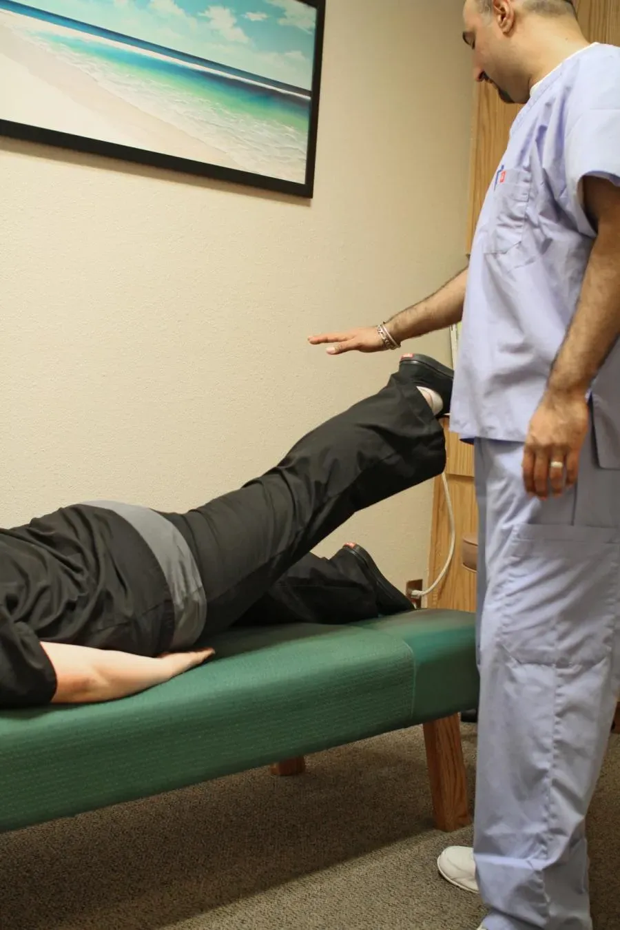 A chiropractor in scrubs performing a leg adjustment on a patient lying on a treatment table at Springtown Wellness Center in Livermore, enhancing wellness through targeted therapy.