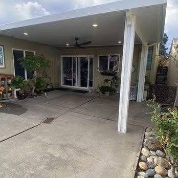 A covered patio area with a ceiling fan, outdoor plants, and glass doors, installed by Sunbusters Patio Cover Company, Inc. in Brentwood.