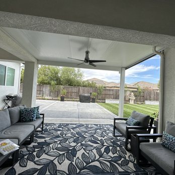 A well-furnished outdoor patio with a ceiling fan, covered by a patio cover, featuring comfortable seating and a patterned rug, installed by Sunbusters Patio Cover Company, Inc. in Brentwood.