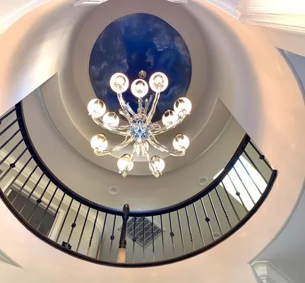 A view from below of a chandelier hanging from a domed ceiling with ornate railings. Installed by TD West Electric, Inc. in Union City.