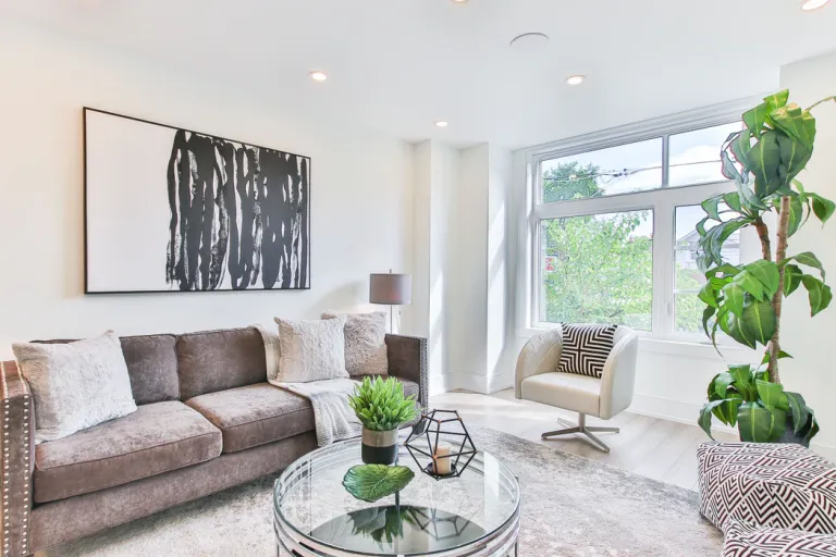 A modern living room in Union City with a gray sofa, a white armchair, large window, indoor plants, and contemporary decor, illuminated by strategic lighting by TD West Electric, Inc.