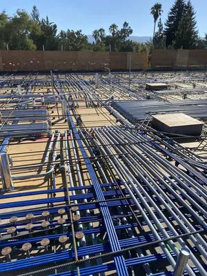 A detailed view of electrical conduits and fittings laid out at a construction site in Union City, installed by TD West Electric, Inc., with trees and a clear sky in the background.