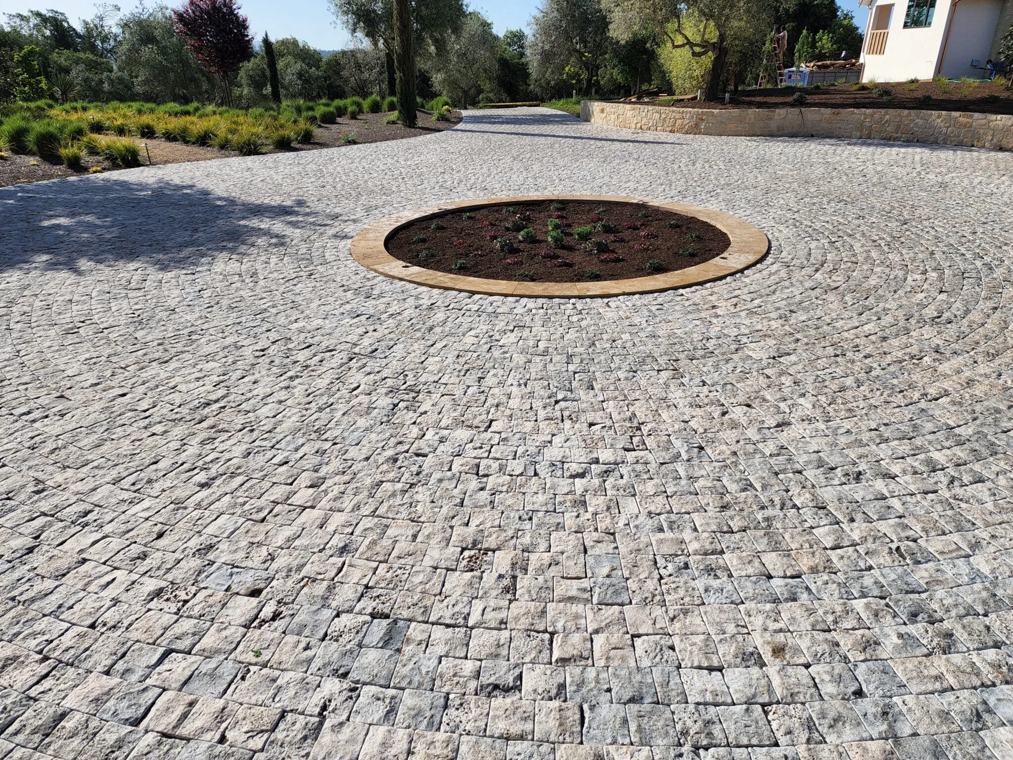 A circular stone driveway with a central landscaped area, showcasing the detailed paver work by The Legacy Paver Group in Santa Rosa.