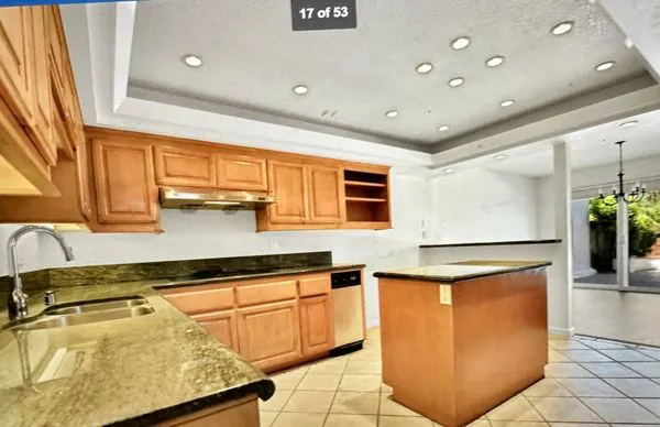 A modern kitchen in Los Gatos with wooden cabinets, granite countertops, and recessed lighting, renovated by The Painting Pros.