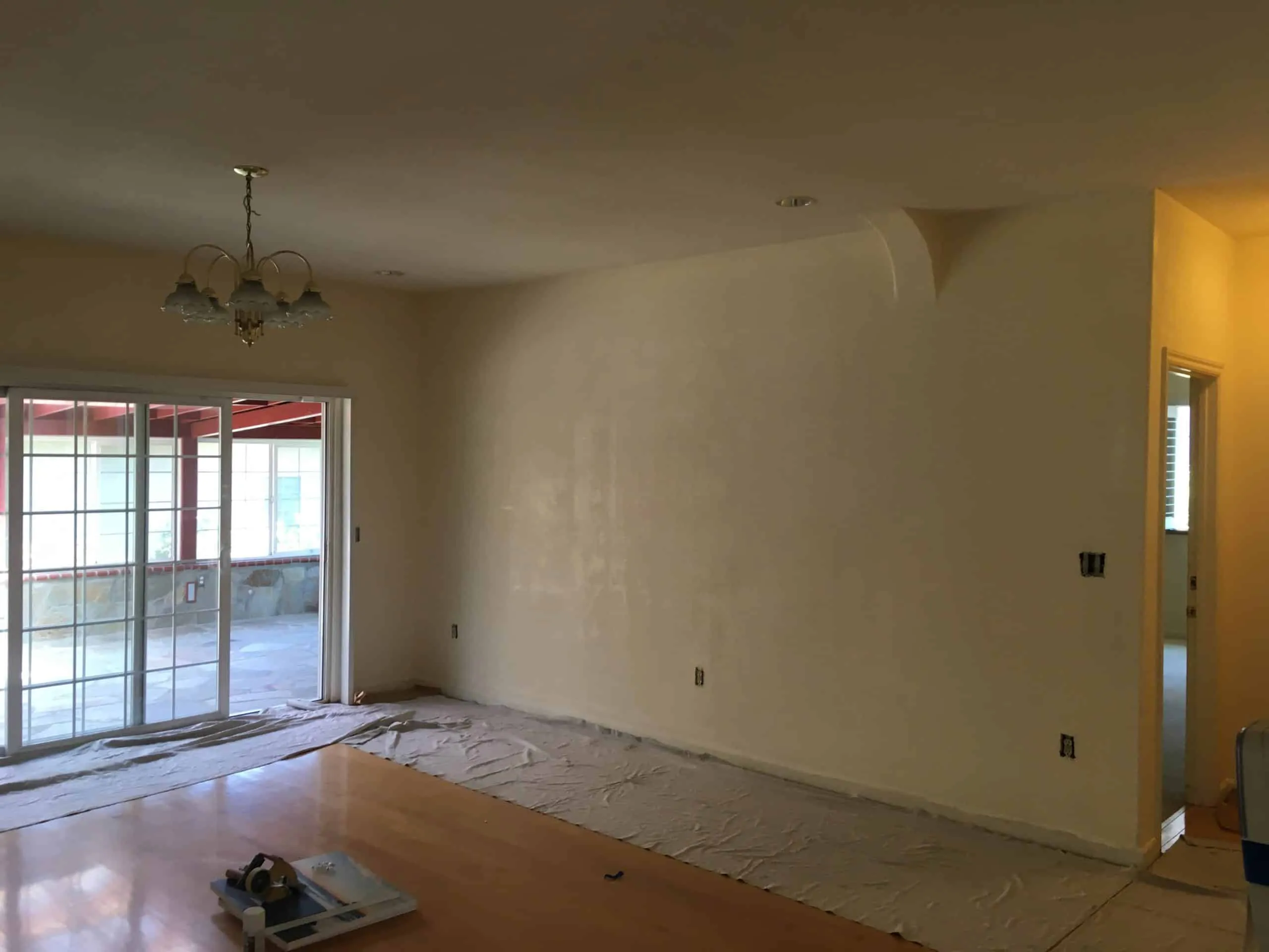 Interior room in Los Gatos with tarp-covered floor, prepared walls, and large sliding glass doors, ready for painting by The Painting Pros.