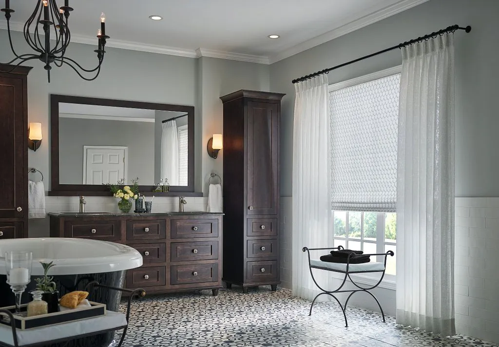 A beautifully designed bathroom with dark wood cabinets, a large mirror, a chandelier, and elegant curtains by The Window Design Studio in Petaluma.