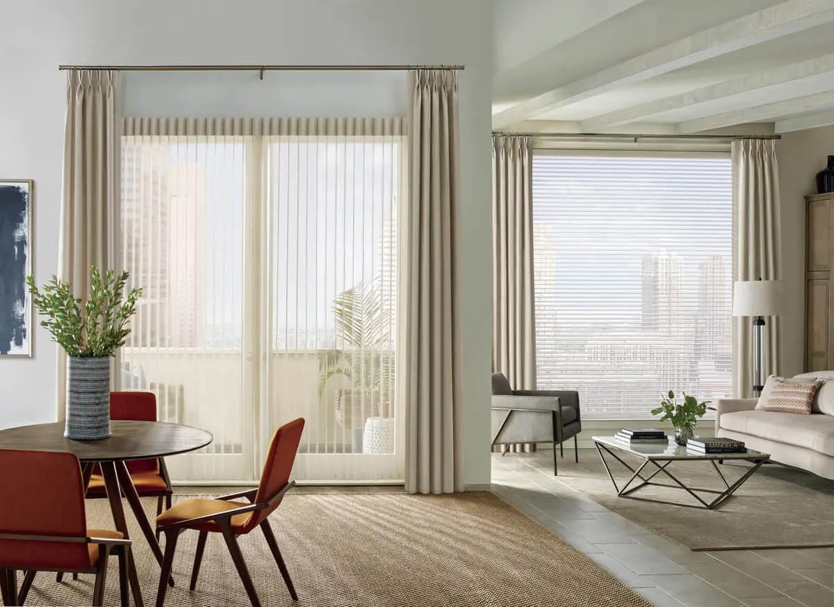 A modern living room featuring elegant floor-to-ceiling curtains by The Window Design Studio in Petaluma, with a dining area and contemporary furniture.