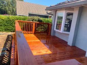 A newly constructed wooden deck with polished timber boards, adjacent to a house with large windows, built by Thompson Construction, Inc. in Healdsburg.