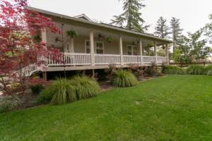 A well-maintained house with a porch surrounded by a lush green lawn and trees, built by Thompson Construction, Inc. in Healdsburg.