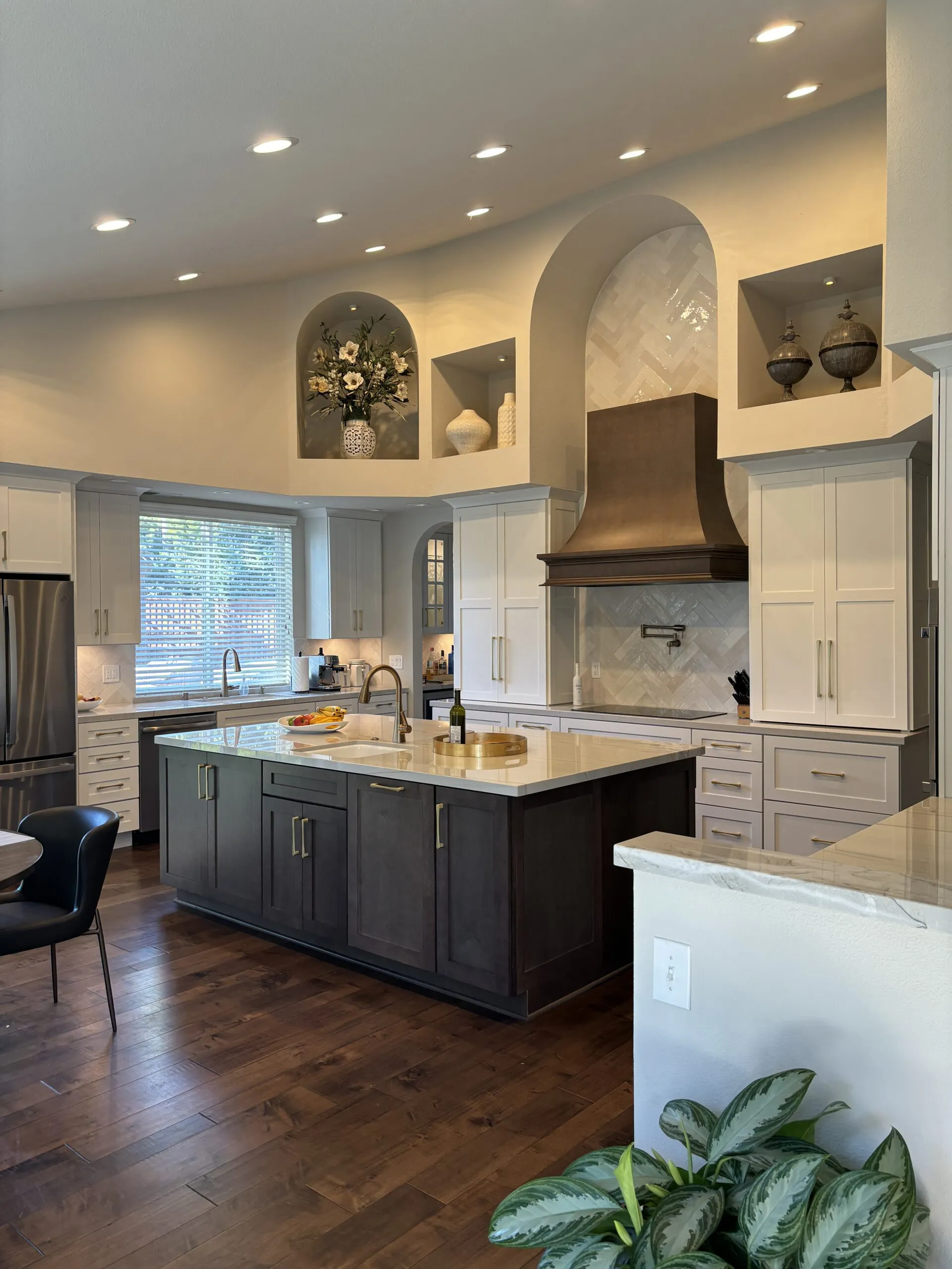 Modern kitchen interior with a large island, elegant cabinetry, wooden flooring, and decorative alcoves, designed by Today'sKitchen&Bath in Livermore.
