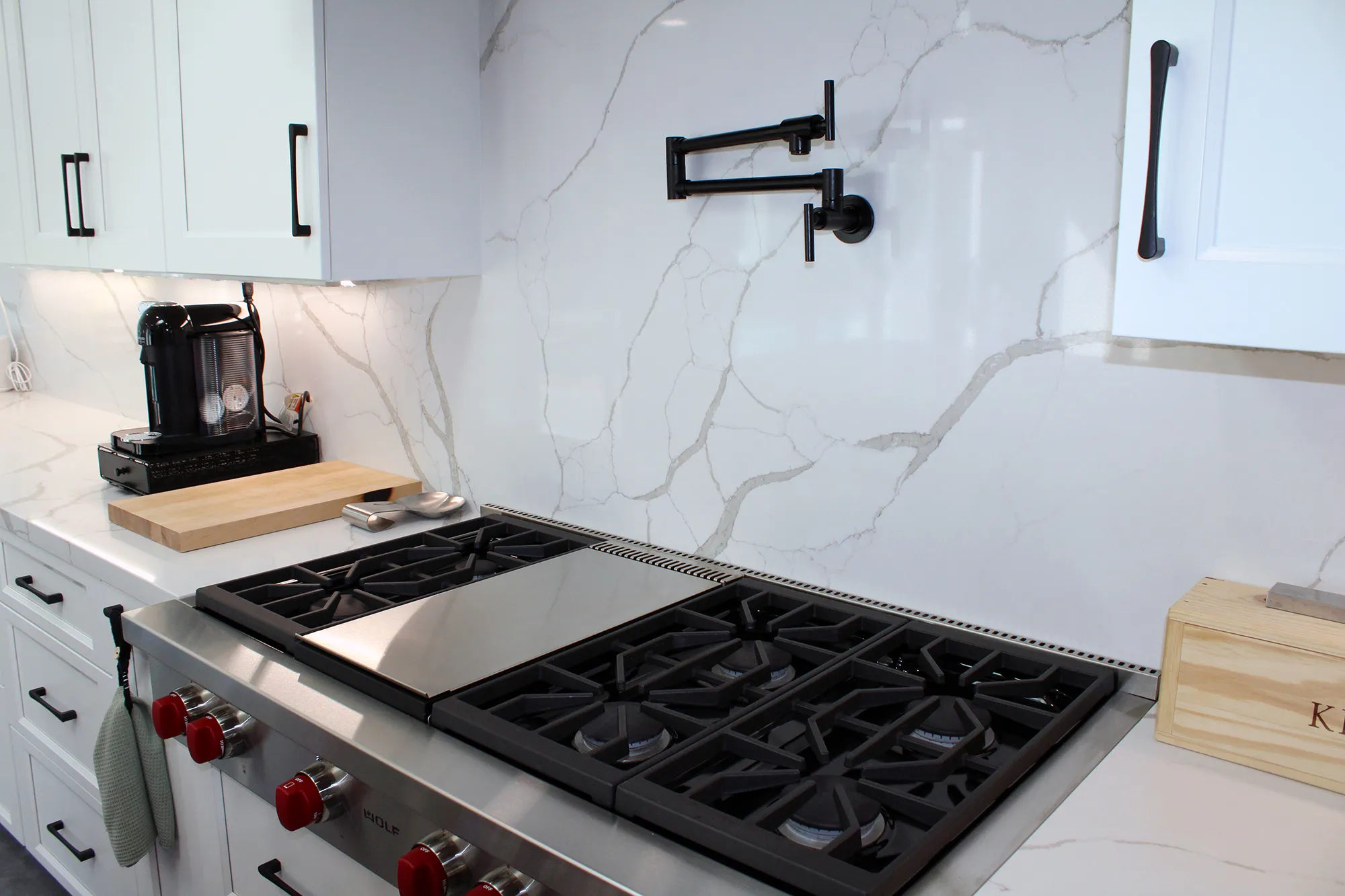 A modern kitchen countertop featuring a gas stove, sleek white cabinetry, and a pot filler, designed by Today'sKitchen&Bath in Livermore.