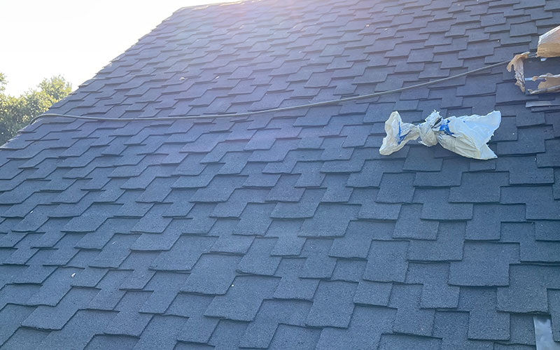 Close-up view of a shingled roof with a cable and plastic bag, showcasing the work of Top Tier Roofing in Morgan Hill.