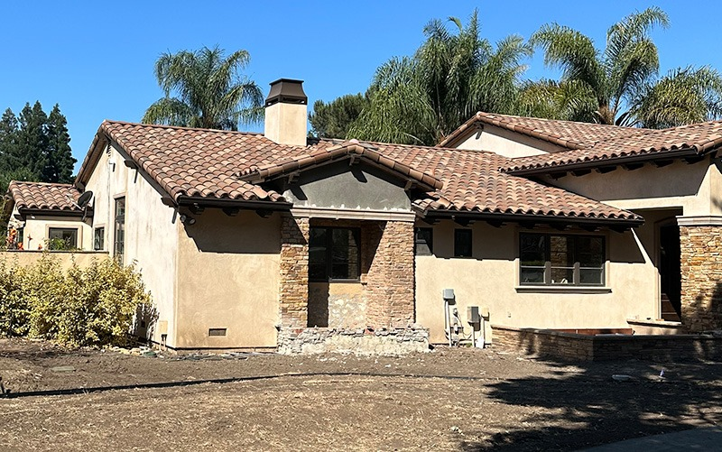 A house in Morgan Hill with a newly installed tile roof by Top Tier Roofing, featuring stucco walls and surrounded by palm trees.