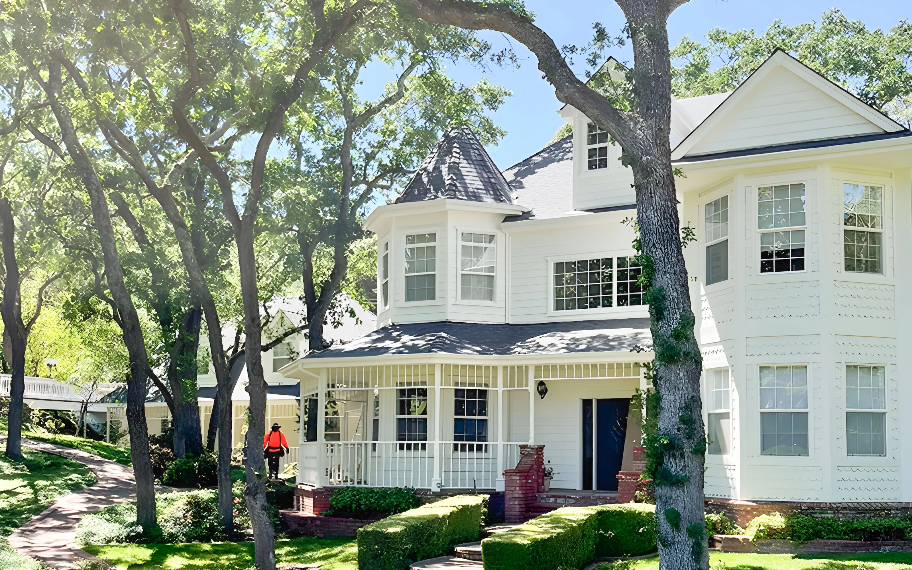 A white house in Morgan Hill with a new roof, surrounded by trees, serviced by Top Tier Roofing.