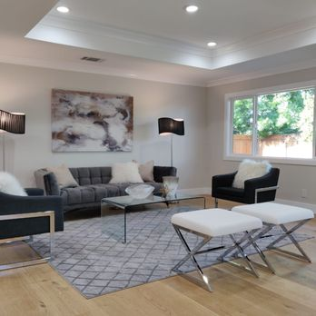 Contemporary living room with gray sofas, abstract art, and large window designed by True Builders in San Jose.
