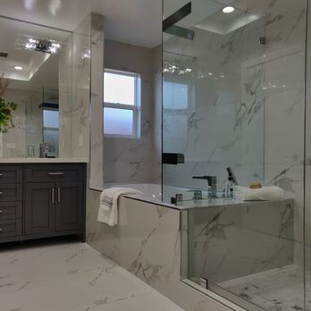 Modern bathroom with marble tile, glass shower enclosure, and dark wood vanity designed by True Builders in San Jose.
