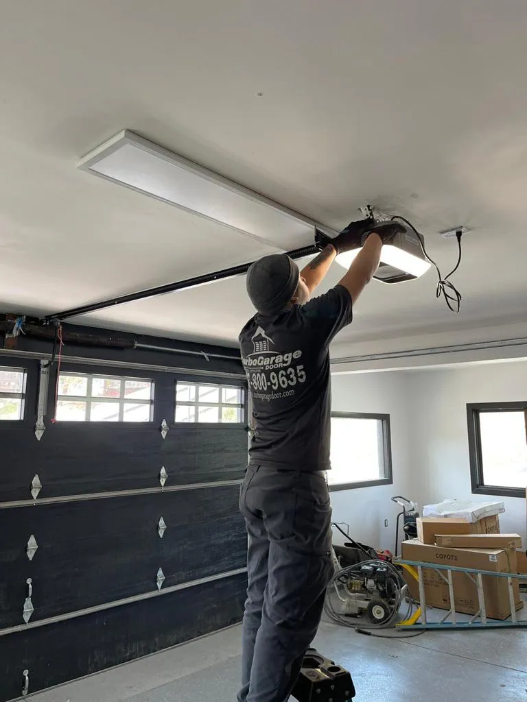 A technician from Turbo Garage Door working on a garage door mechanism in a Santa Rosa garage.