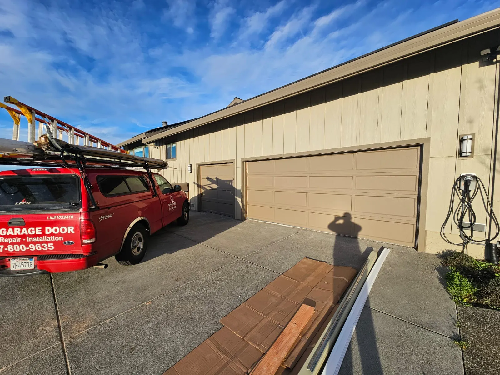 A red Turbo Garage Door service vehicle parked beside a residential garage in Santa Rosa, with tools and materials nearby.