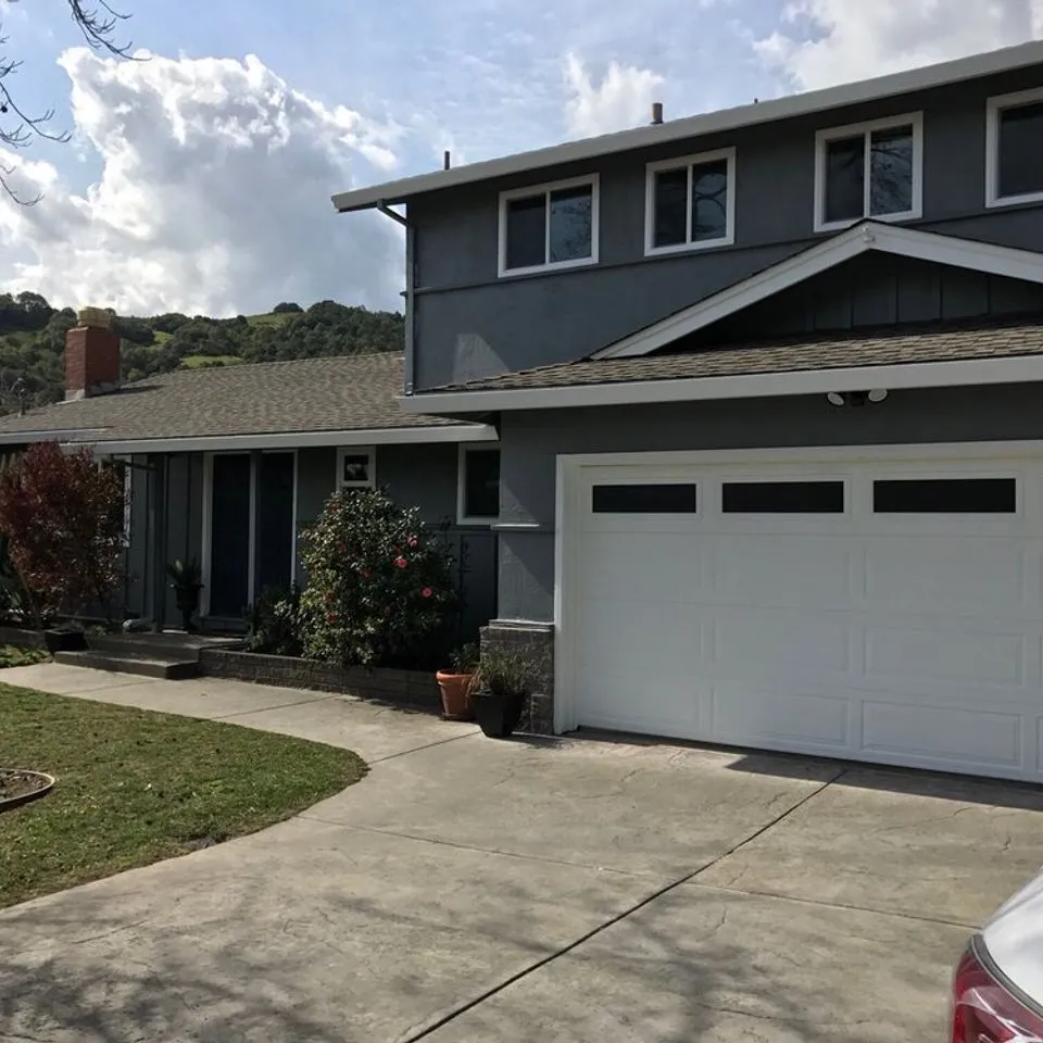 A modern gray house with a well-maintained garden and driveway, showcasing exterior painting work by Unique Painting Services in Novato.