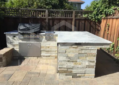 Outdoor stone kitchen with a barbeque and counter in a San Jose backyard, installed by Unique Pavers.