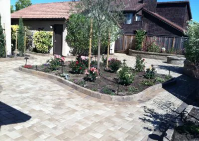 A beautifully landscaped yard in San Jose featuring a paved walkway and a garden area, showcasing the work of Unique Pavers.
