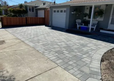 A neat, patterned driveway and front area of a house with gray pavers, installed by Unique Pavers in San Jose.
