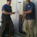 Two technicians from Water Heaters Masters Inc. stand next to an installed water heater unit in Vacaville.